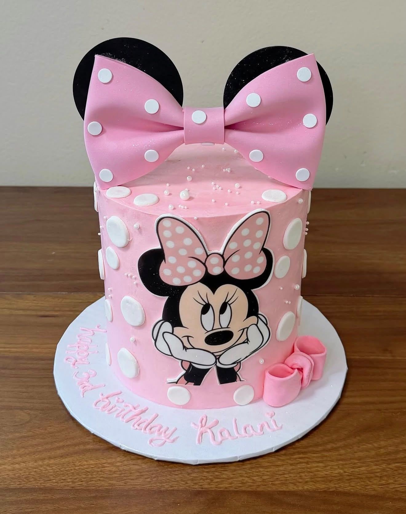Tarta de cumpleaños rosa de lunares con gran lazo de fondant, temática Minnie
